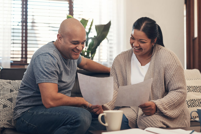 A couple sitting together in their living room looking at documents