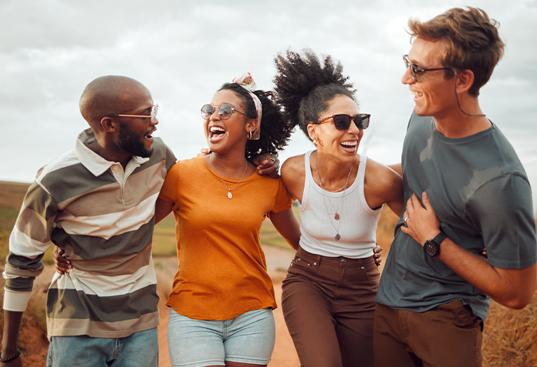 Young adults standing outside together with arms around each other