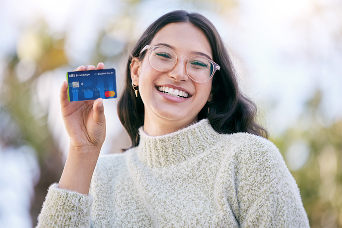 Woman smiling and holding up a Broadview Secured credit card